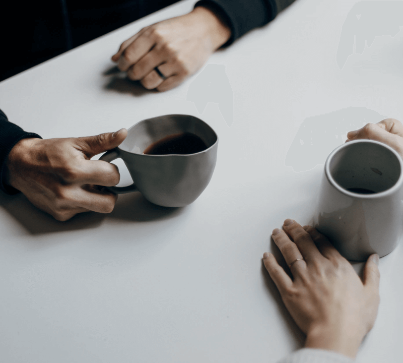 close up of hands holding coffee mugs on table