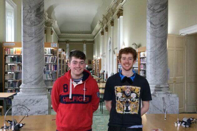 Two male students smiling in library