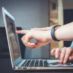 Close up of laptop with fingers pointing at screen