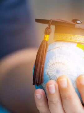 hand holding globe with mortarboard perched on top