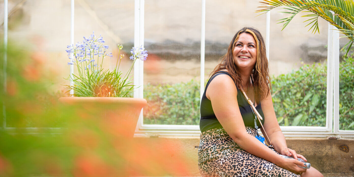 young woman smiling, sitting in conservatory