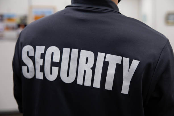 Rear view of a security guard in uniform patrolling in an art gallery in a commercial building.